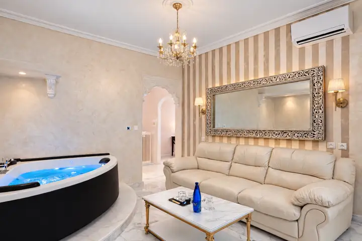 Aegean Spa Suite with indoor jacuzzi, sauna and rooftop jacuzzi, sea view – living room with chromotherapy jacuzzi, leather sofa and chandelier · Panorama Suites & Spa, Stomio