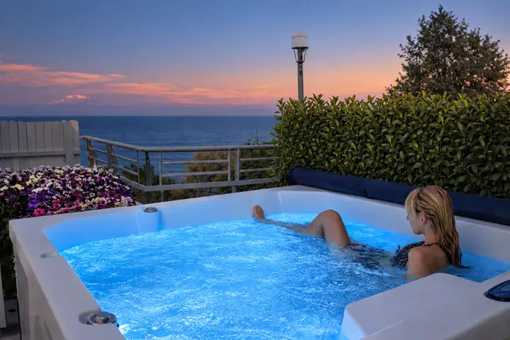 Aegean Spa Suite with indoor jacuzzi, sauna and rooftop jacuzzi, sea view – relaxing in the lit rooftop jacuzzi at dusk with sea view · Panorama Suites & Spa, Stomio