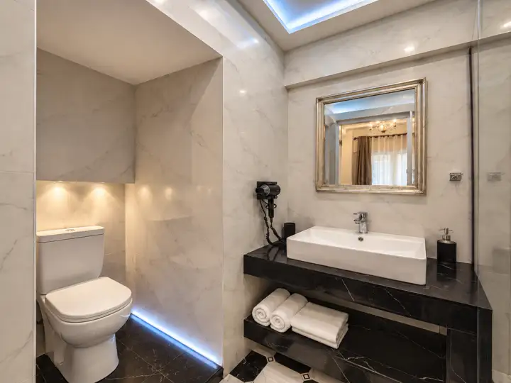 Sea Breeze Double Room with outdoor heated jacuzzi, sea view – marble bathroom with vessel sink and black marble vanity · Panorama Suites & Spa, Stomio