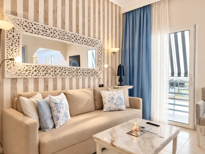 Horizon Suite with indoor and outdoor jacuzzi, sea view – living room with tabletop fireplace and sea-view balcony · Panorama Suites & Spa, Stomio