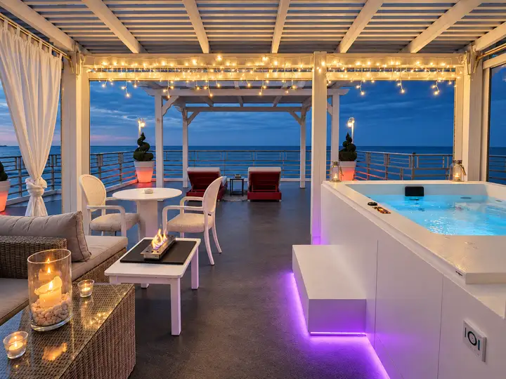 Master Sky Suite with heated jacuzzi, sauna and rooftop terrace, sea view – jacuzzi pavilion at dusk with table fireplace, candles and fairy lights · Panorama Suites & Spa, Stomio