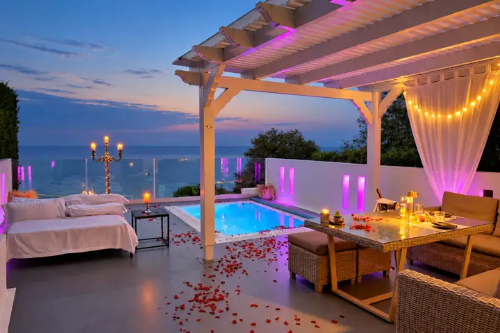 Sunrise Suite with two bedrooms, heated infinity pool and jacuzzi, sea view – romantic evening set-up on the pool terrace with candles and rose petals · Panorama Suites & Spa, Stomio