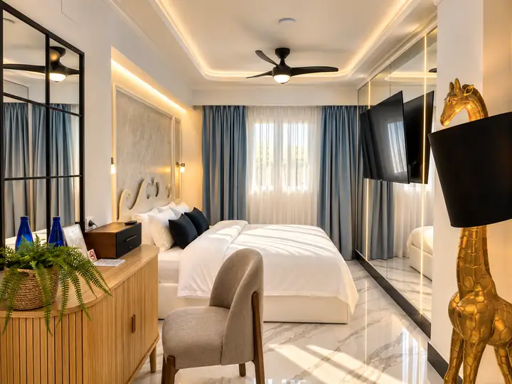 Sunrise Suite with two bedrooms, heated infinity pool and jacuzzi, sea view – second bedroom with double bed and wall-mounted TV · Panorama Suites & Spa, Stomio