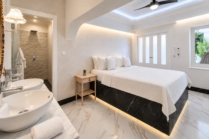 Sunrise Suite with two bedrooms, heated infinity pool and jacuzzi, sea view – bedroom with illuminated marble bed base and walk-in rain shower · Panorama Suites & Spa, Stomio